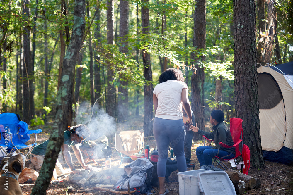 Friends enjoying weekend getaway, relaxing at campsite in woods Friends enjoying weekend getaway, relaxing at campsite in woods