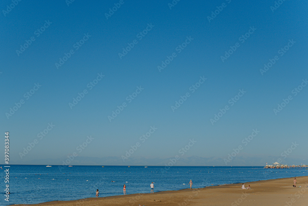 Small silhouettes of many people of different ages have fun on sunny summer tropical beach during summer vacations. Small silhouettes of many people of different ages have fun on sunny summer tropical beach during summer vacations.