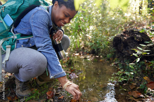 Black female botanist examines plants on trail photo