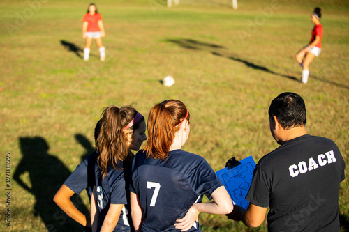 Teenage soccer coach teaches plays with female team