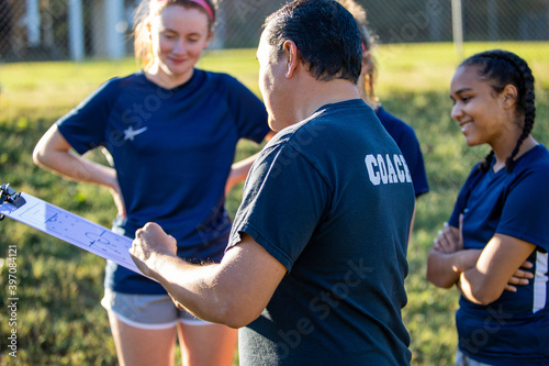 Teenage soccer coach teaches plays with female team