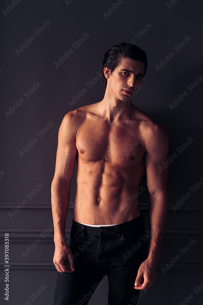 Fototapeta premium Frontal portrait of a fit, athletic young man on dark grey background.