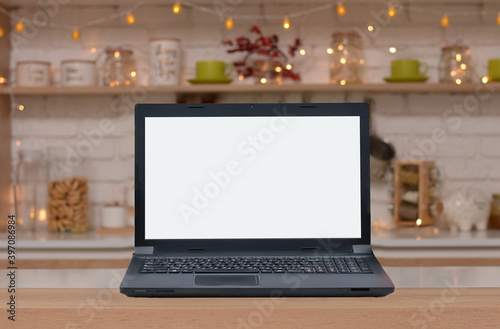 Laptop with blank screen on the background of Christmas kitchen.Copy space for text