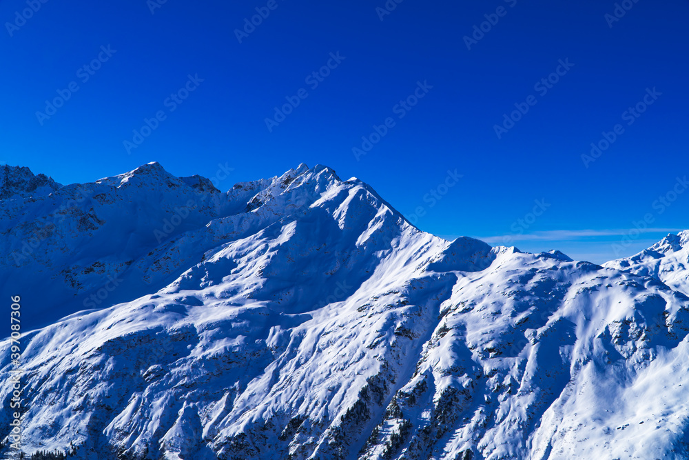Magical blue Austrian Alps panorama - background image of snowy mountains and peaks near Zürs, Austria