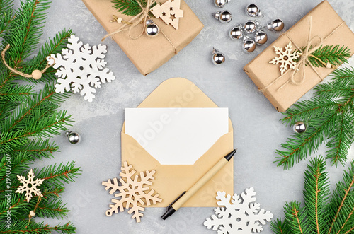 Greeting card with envelope and pen, mockup with fir tree branches, gift boxes and christmas decorations