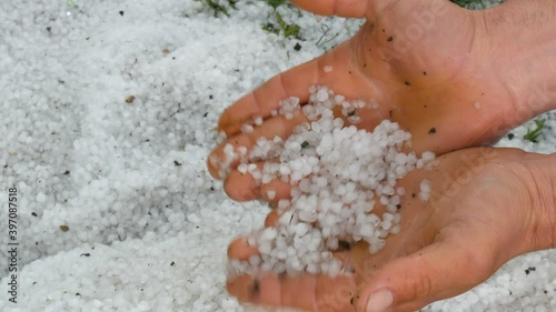 Natural disaster, male hands hold a lot of hail icy snowin his hands. photo