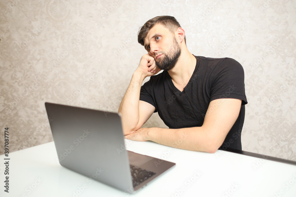 young man sitting at a laptop at home in quarantine young man sitting at a laptop at home in quarantine