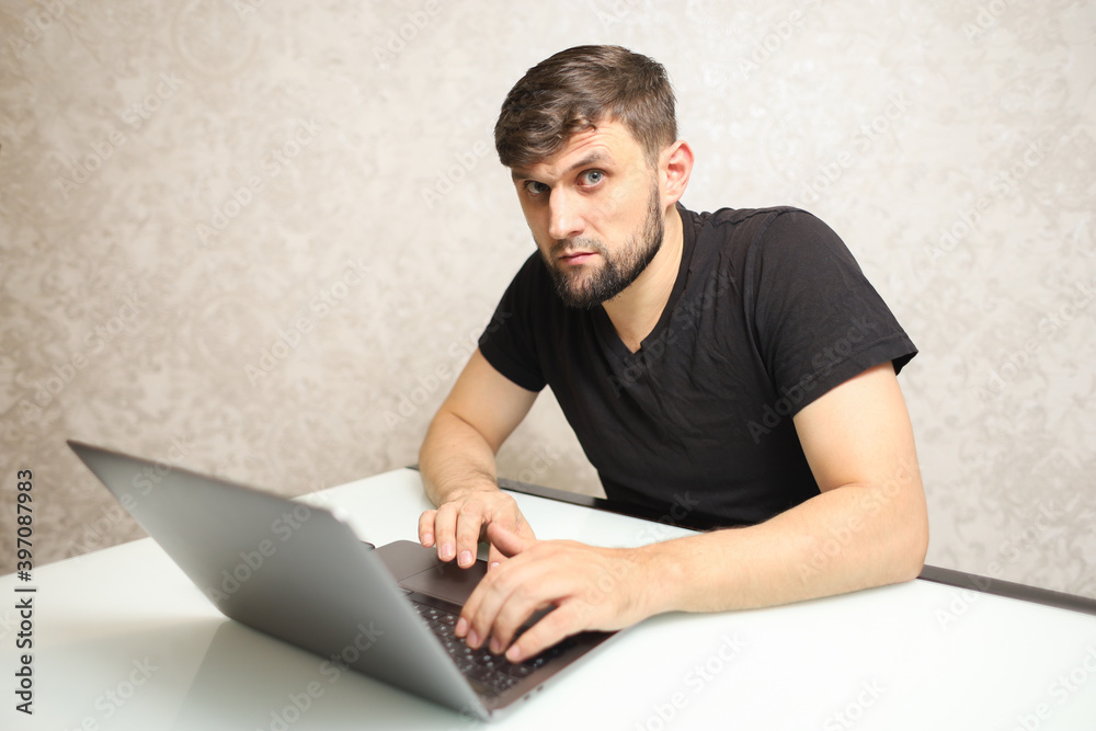 a man is typing on a laptop and looking at the camera a man is typing on a laptop and looking at the camera