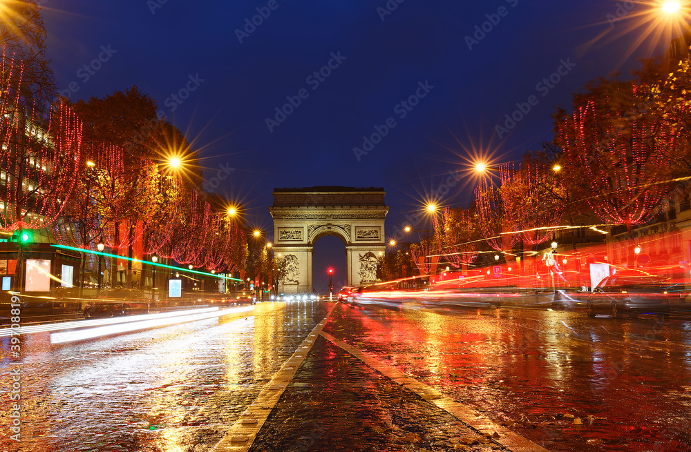 The Triumphal Arch and Champs Elysees avenue illuminated for Christmas at rainy night ,Paris, France.