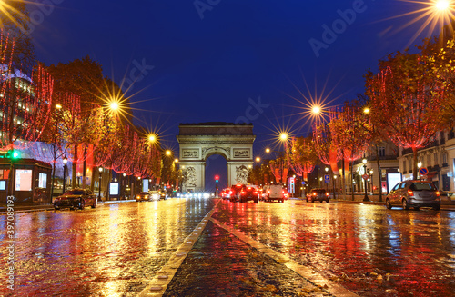 The Triumphal Arch and Champs Elysees avenue illuminated for Christmas at rainy night ,Paris, France.