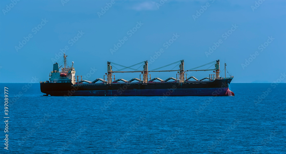 A side view of lightly laden bulk carrier vessel at sea approaching the Singapore Straits in Asia in summertime