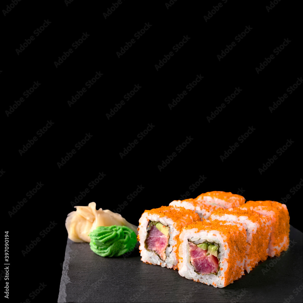 California Tuna Roll In Orange Tobiko Roe Isolated On Black Background. Japanese Cuisine Sushi Set With Tuna And Avocado On Grey Black Plate Copy Space Square Banner. California Tuna Roll In Orange Tobiko Roe Isolated On Black Background. Japanese Cuisine Sushi Set With Tuna And Avocado On Grey Black Plate Copy Space Square Banner.