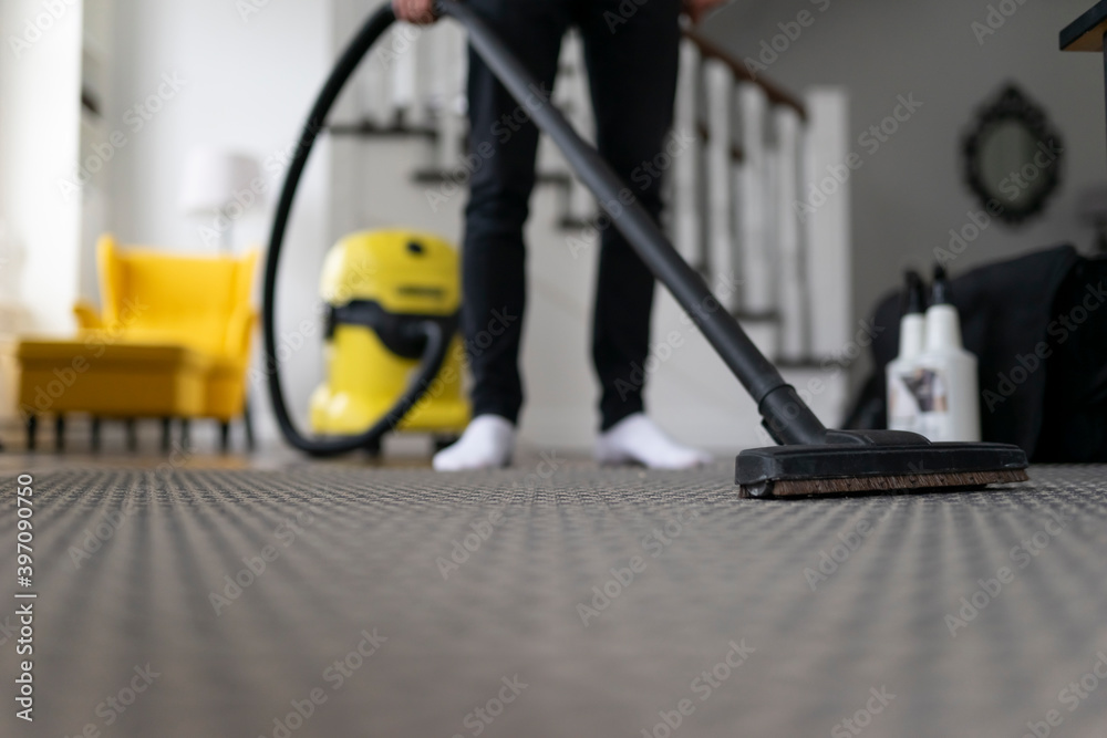 Man vacuuming the carpet in the room. House cleaning process