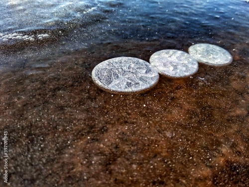 frozen air bubbles in the form of circles on the river in winter