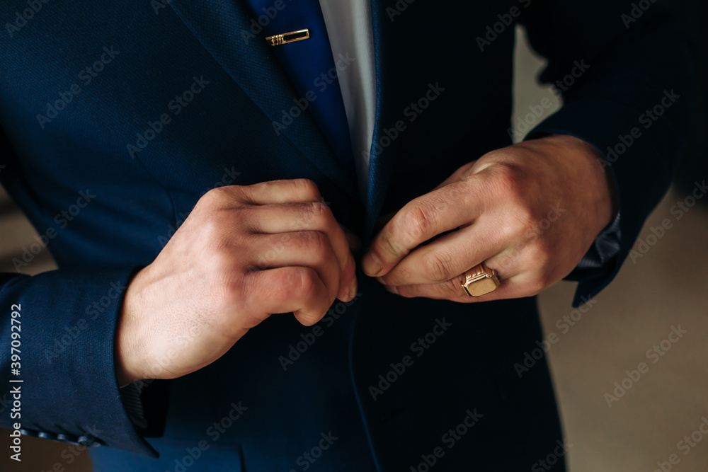 A stylish man in a suit fastens his buttons, preparing to leave. Preparing for the wedding