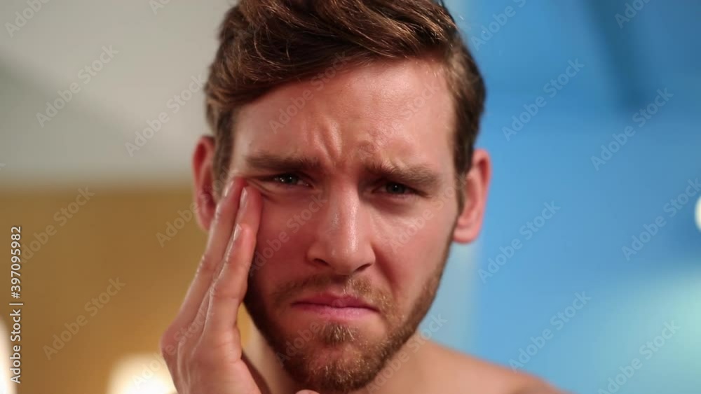 Man examining his face in mirror Man examining his face in mirror
