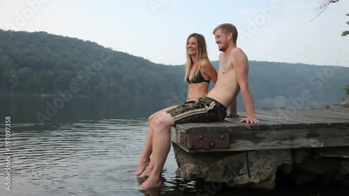 Couple sitting on edge of dock at lake