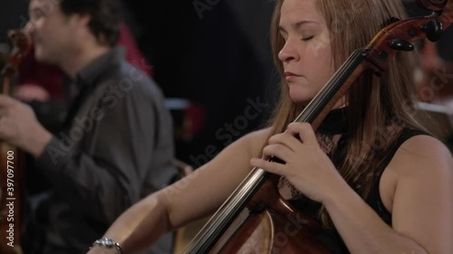 Woman playing cello with band in background photo