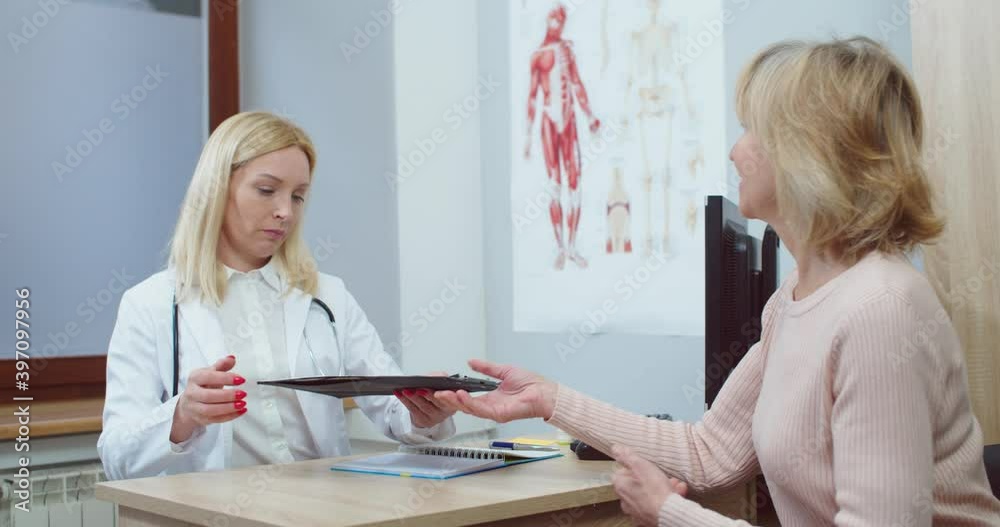 Portrait of professional female Caucasian doctor in white coat meeting senior patient woman while sitting in hospital cabinet and taking medical history. Physician concept. Doctor appointment Portrait of professional female Caucasian doctor in white coat meeting senior patient woman while sitting in hospital cabinet and taking medical history. Physician concept. Doctor appointment