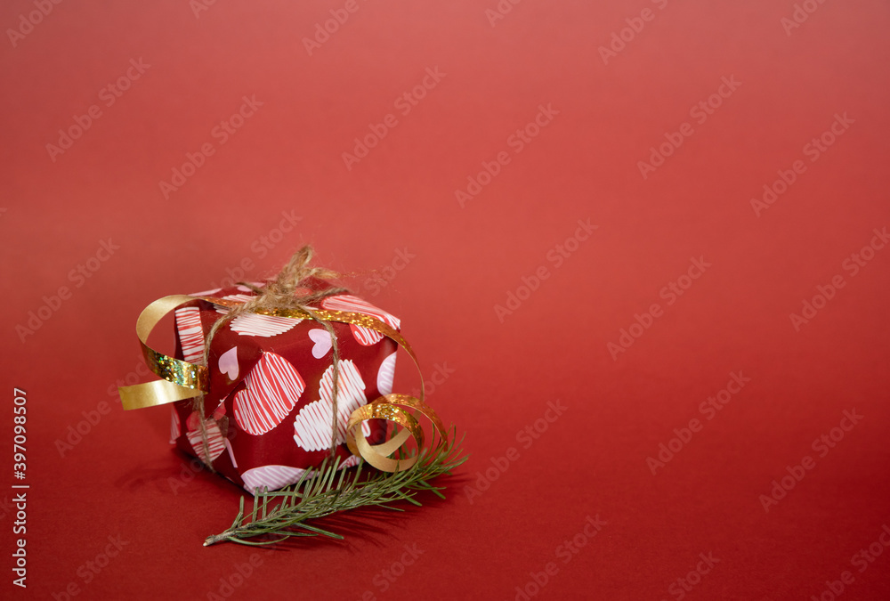Decorated box with a gift for New Year and Christmas. Red background, free space for insertion.