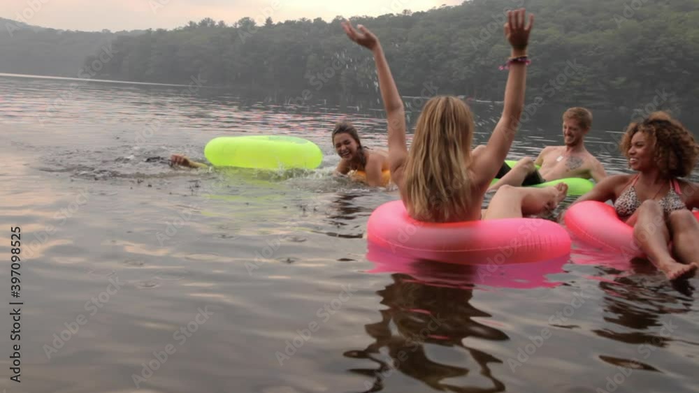 Friends floating on lake in inner tubes