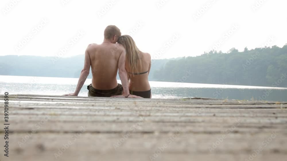 Couple sitting on edge of dock at lake