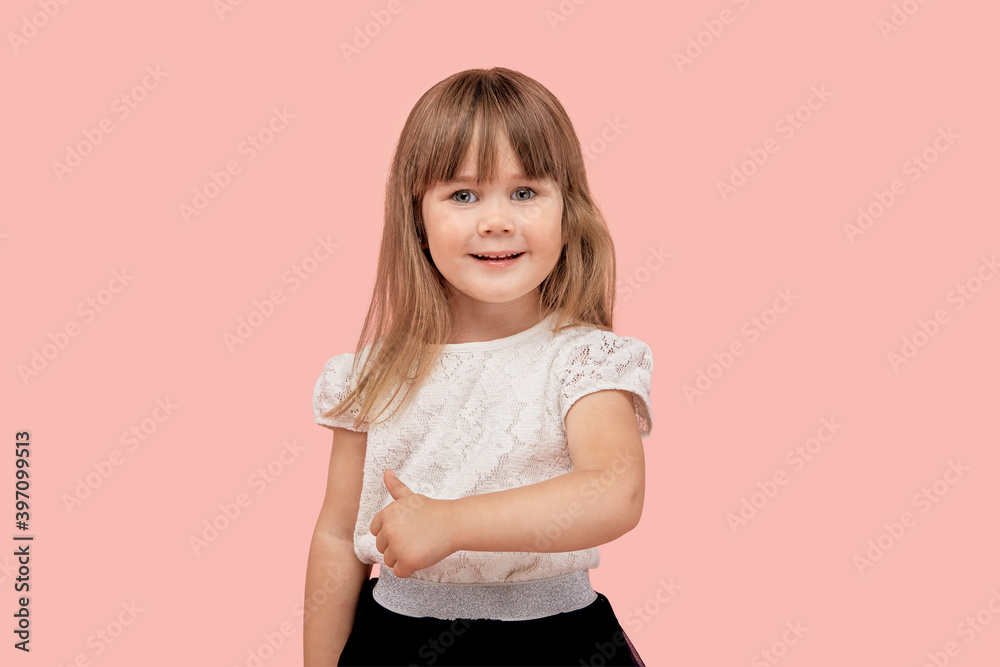 Cute beautiful little girl smiles and shows a thumbs up gesture, looks at the camera. Pink isolated background. Cute beautiful little girl smiles and shows a thumbs up gesture, looks at the camera. Pink isolated background.