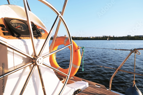 Yacht steering wheel on sunny day wallpaper. Water sport background. White boat cruise banner. Metal rudder on ship. Orange lifebuoy on yacht. Freedom landscape wallpaper. High quality photo © Alexandra