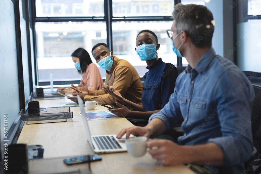Diverse colleagues wearing face masks working in office Diverse colleagues wearing face masks working in office
