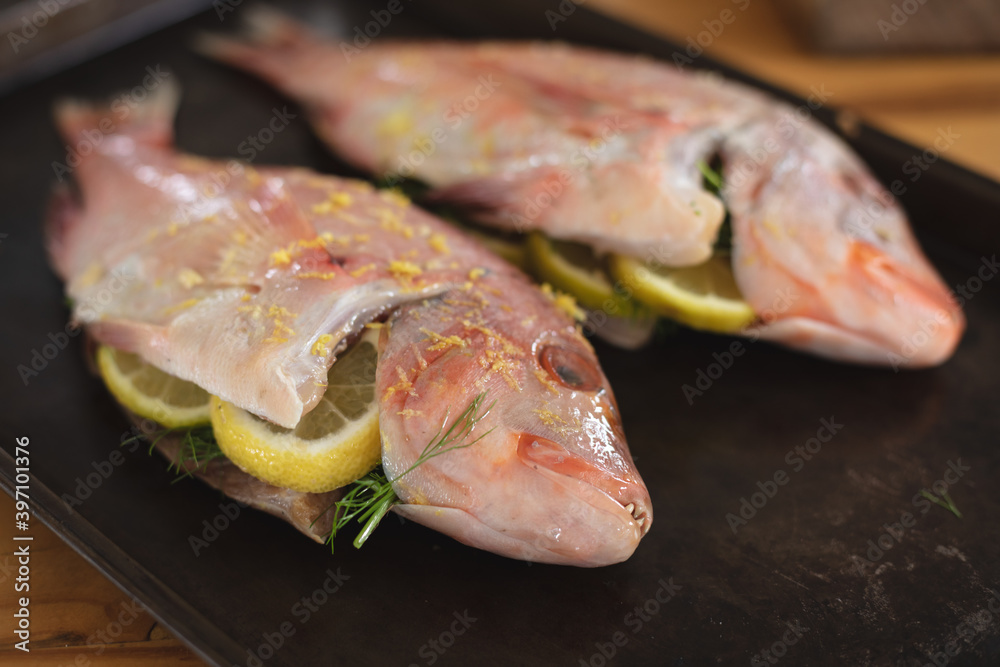 Close up view of roasted fish on black wooden board Close up view of roasted fish on black wooden board