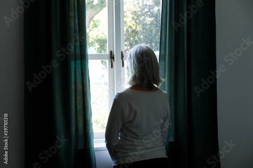 Rear view of senior caucasian woman looking out of window at home photo