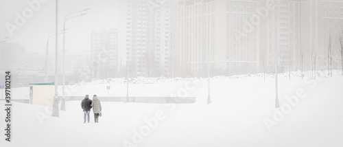 An adult couple walks through a snowy city. horizontal, Loneliness in a big city.