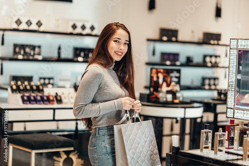 Happy beautiful Asian girl smiling young girl buys perfume cosmetics in the store