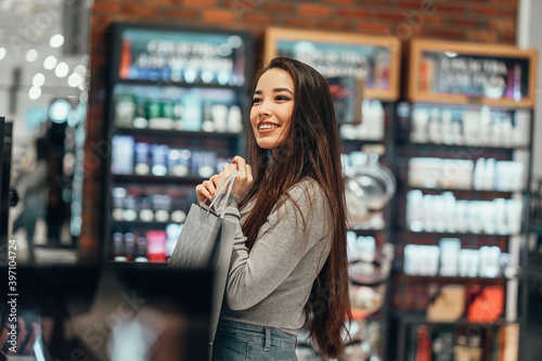 beautiful smiling Asian girl chooses buys cosmetics in the store. shopping