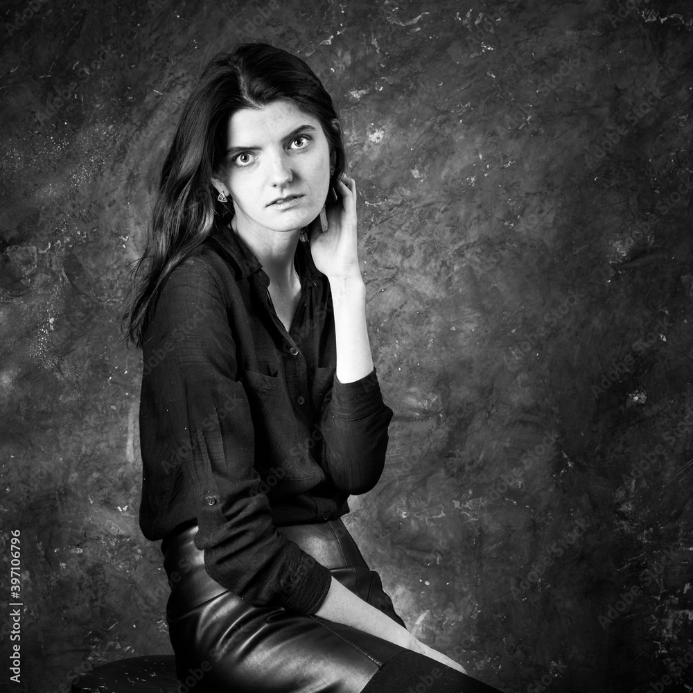 Studio portrait of young beautiful woman in a leather skirt. Studio portrait of young beautiful woman in a leather skirt.