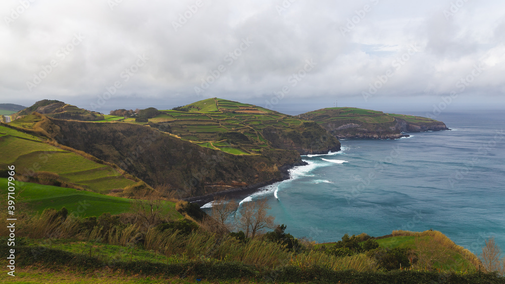 Sao Miguel island Portugal cloudy weather Atlantic ocean shore coast hill mountain  green fields waves blue water 