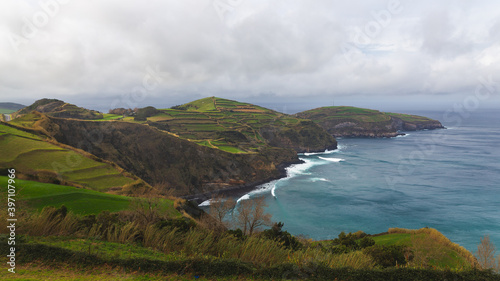 Sao Miguel island Portugal cloudy weather Atlantic ocean shore coast hill mountain green fields waves blue water 