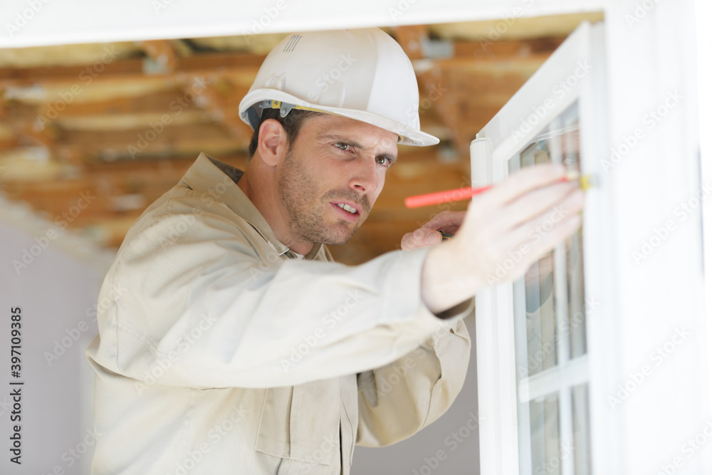 builder measuring a window using a tape measure and pencil builder measuring a window using a tape measure and pencil
