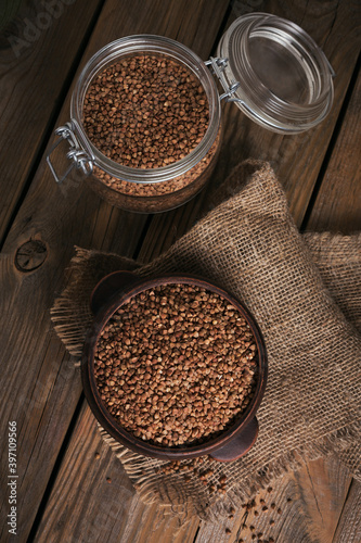 Bowl of dry raw buckwheat groats on a wooden background. Cooking buckwheat porridge concept.