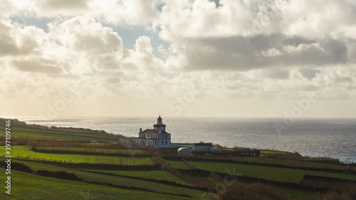 Sao Miguel island Portugal shore lighthouse Atlantic ocean day sunshine sunlight white clouds water field green 