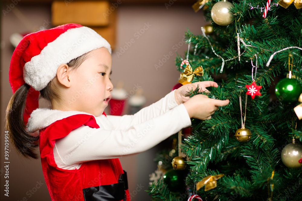 young girl decorating Christmas tree at home young girl decorating Christmas tree at home