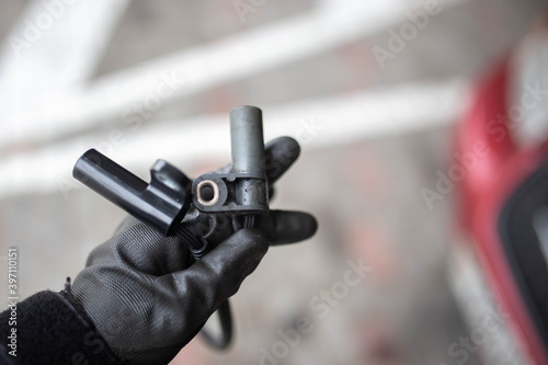 electromagnetic crankshaft position sensor of a car engine in the hands of an auto mechanic.