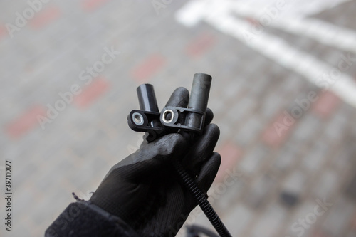 Fotografija electromagnetic crankshaft position sensor of a car engine in the hands of an auto mechanic