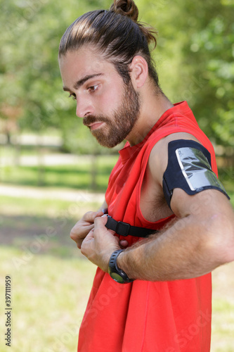 male jogger controls heart beats on training outdoor