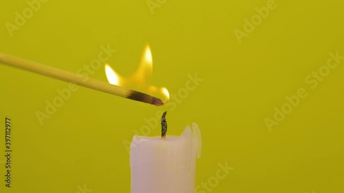 Close-up of candle wick lit with splinter on yellow background and then it is blown out