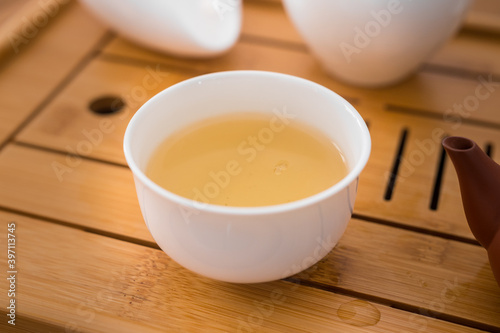 Beautiful porcelain tea cup on a bambou tray close up shot. Hydrating pale liquor in it.
Fresh natural Si Ji Chun, a rolled oolong tea.