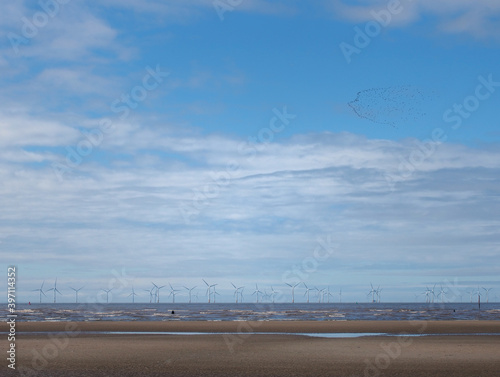 the beach at blundell sands in sefton near southport with waves braking on the beach and the wind turbines at burbo bank visible in the distance photo