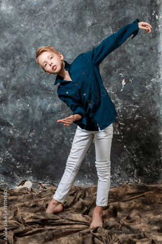 Young dancer dressed in white jeans and blue shirt doing figures studio portrait