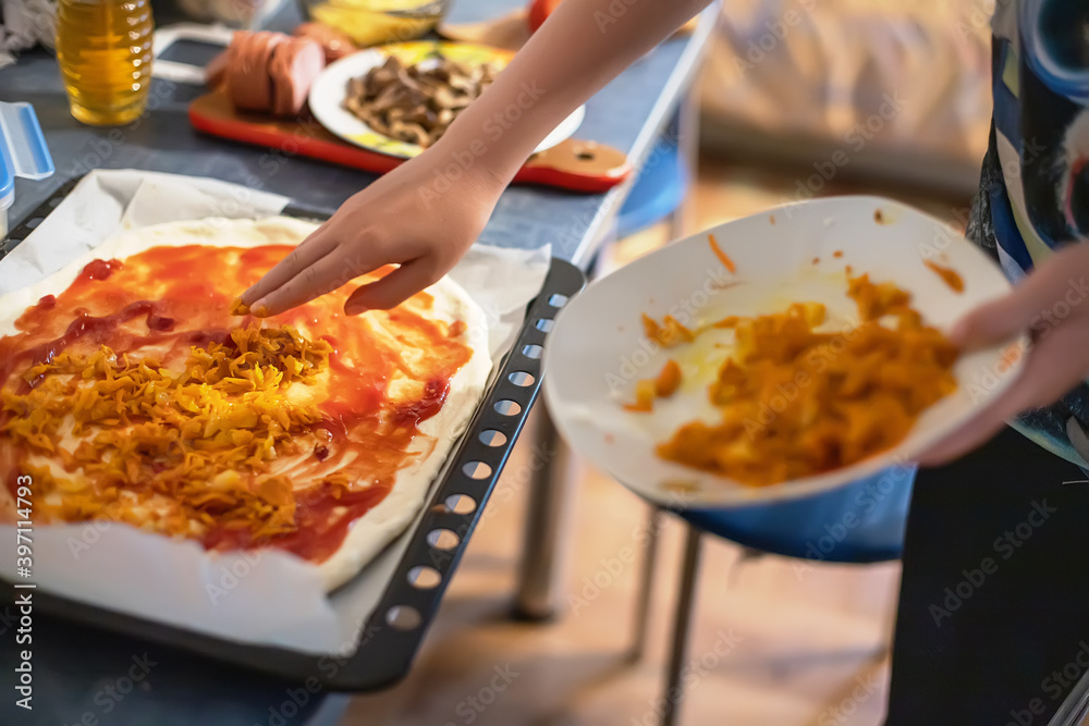Hand Adding ingredients on homemade pizza. Simple food made from cheap foods. Preparing food at home. Hand Adding ingredients on homemade pizza. Simple food made from cheap foods. Preparing food at home.