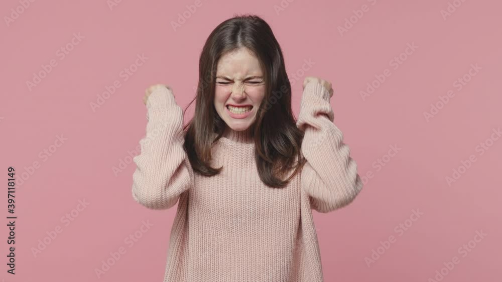 Angry irritated brunette young woman 20s years old in pastel sweater isolated on pink color background studio. People lifestyle concept. Screaming swearing spreading hands standing with arms akimbo Angry irritated brunette young woman 20s years old in pastel sweater isolated on pink color background studio. People lifestyle concept. Screaming swearing spreading hands standing with arms akimbo